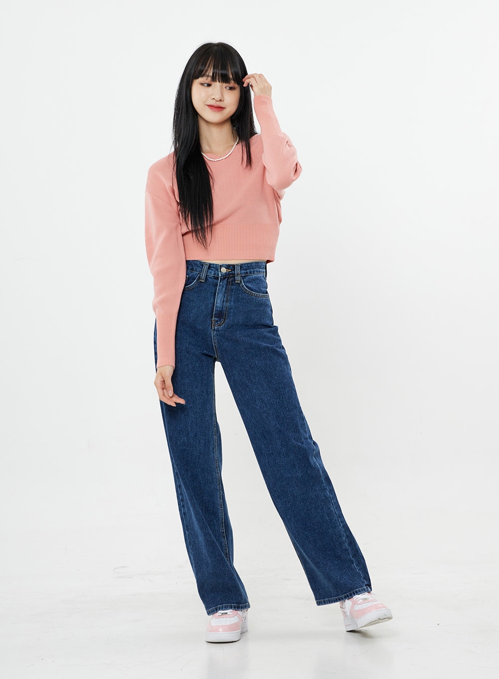 Basic Long Denim Pants BS28 in mid-blue, front full-body on model with playful pose, high-rise straight-fit wide-leg cotton denim, styled with pink crop sweater and sneakers.