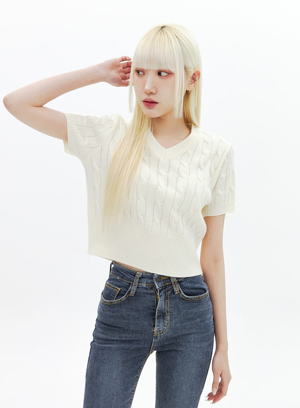 Skinny Ankle Jeans BA321 in dark blue denim, waist-up shot on model looking aside, high-rise front pocket stitching detail visible, layered with cream cable-knit crop top.