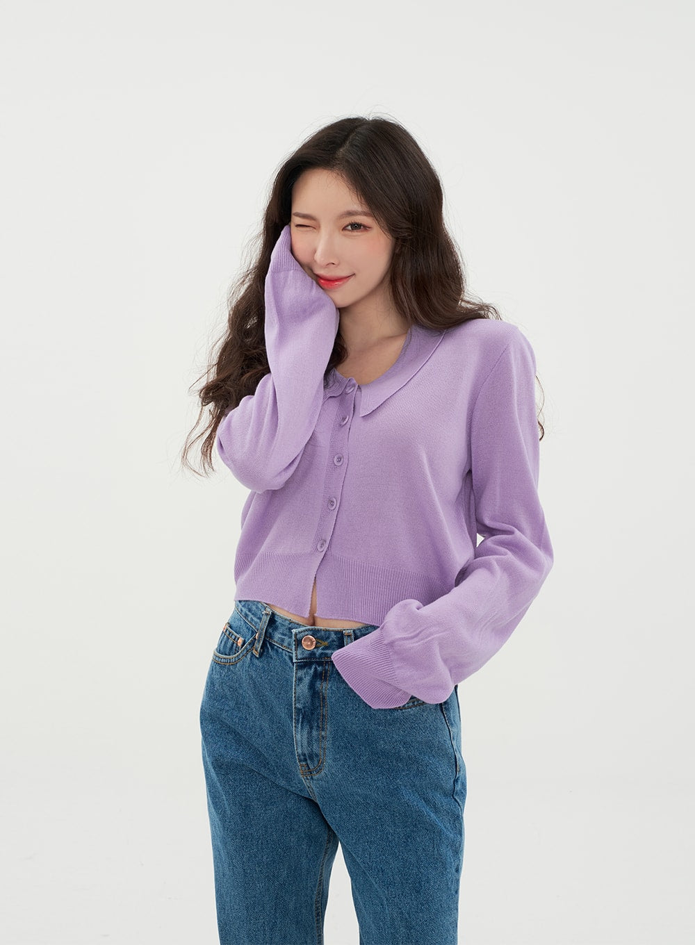 Semi Wide Jeans BM21 in mid-blue denim, front upper-body close-up on model smiling, high-rise waistband with button fastening detail, styled with cropped lavender knit cardigan.
