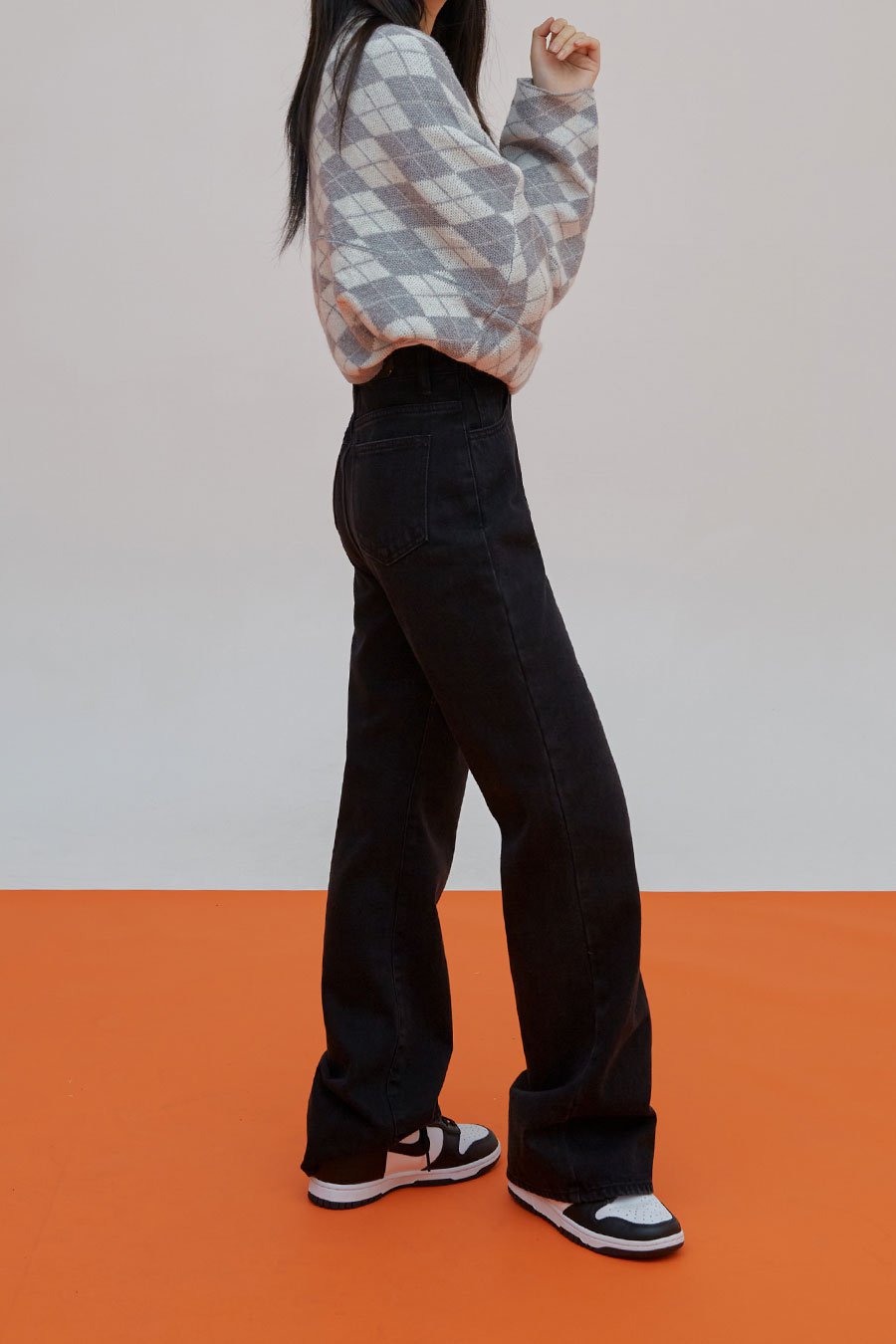 Straight Leg Pants J23 in black, side view on model, straight-leg silhouette with back pocket detail, high-rise waist, styled with argyle cardigan and sneakers.