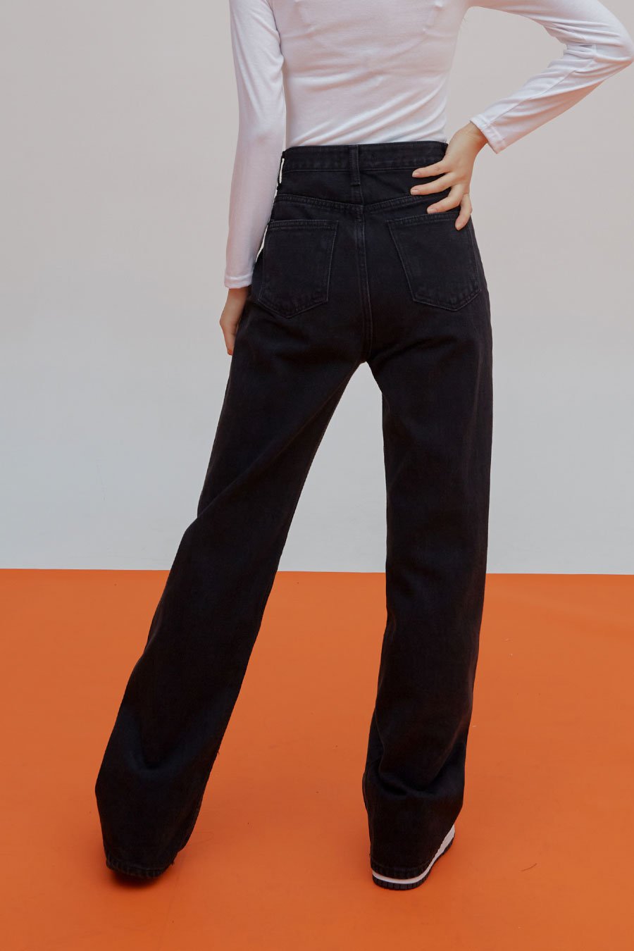 Straight Leg Pants J23 in black, back full-length view on model, two back patch pockets, high waist, straight cotton denim leg, paired with white long-sleeve top.
