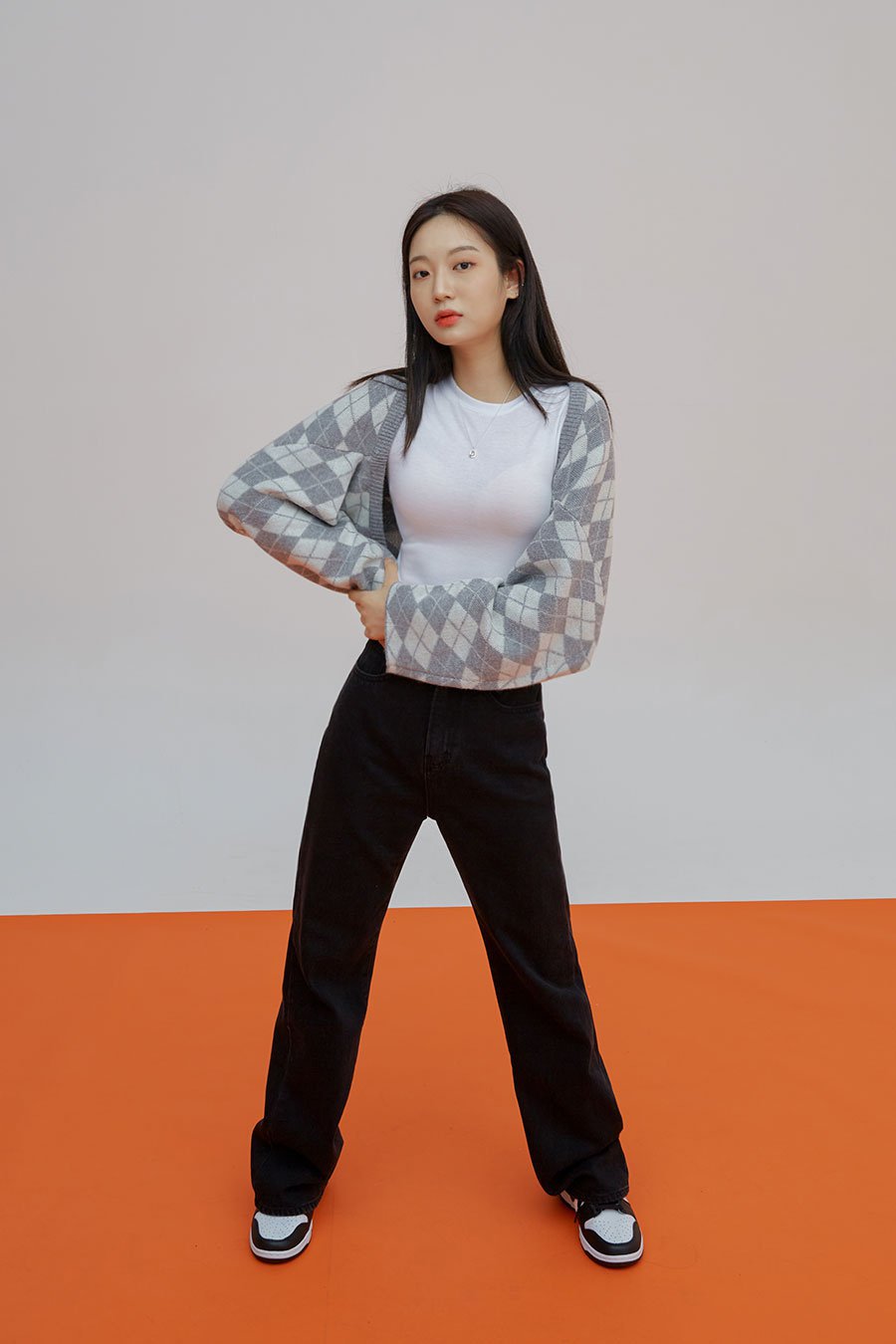 Straight Leg Pants J23 in black, full-length front shot on model standing wide, long straight-fit cotton denim, high rise, styled with argyle cardigan and white tee.