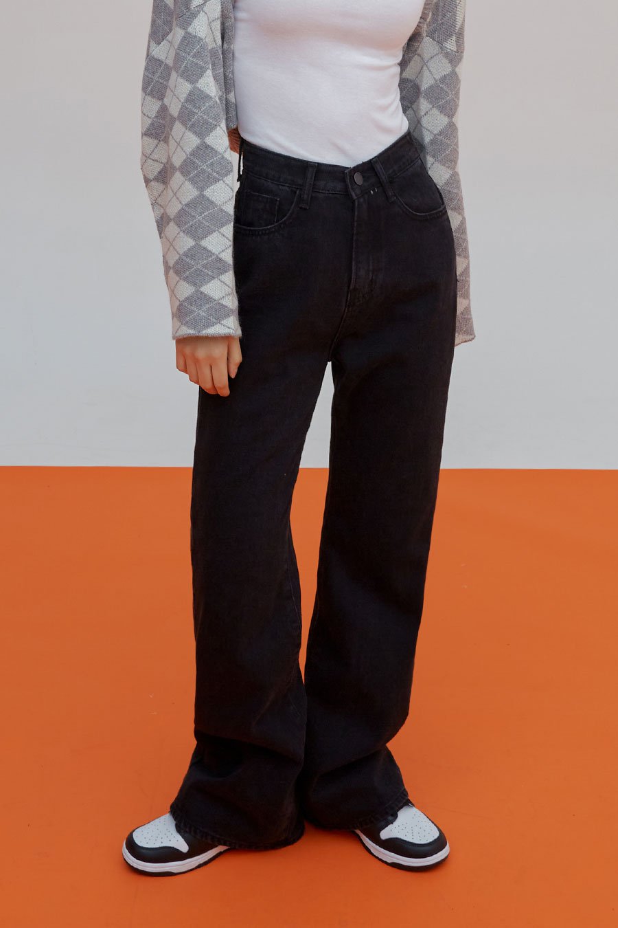Straight Leg Pants J23 in black, front close-up waist-to-hem on model, high-rise waistband with button fly, front pockets, straight cotton denim, with sneakers at hem.